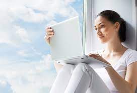 девушка у окна с облаками с ноутбуком